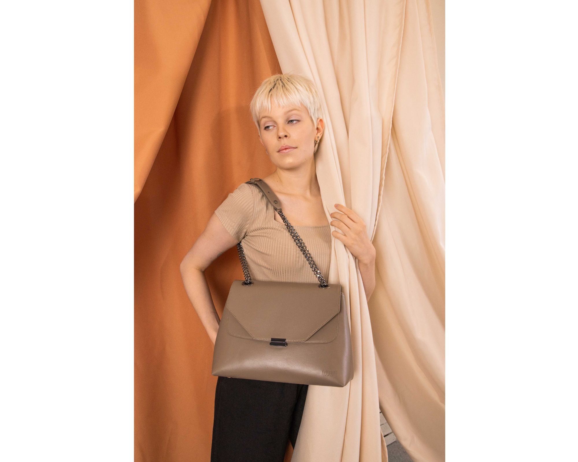 Woman holding a taupe shoulder bag by nuuwai